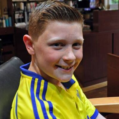 A young boy wearing a yellow shirt with blue stripes is smiling