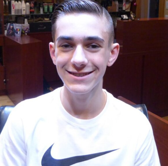 A young man wearing a white nike shirt smiles for the camera