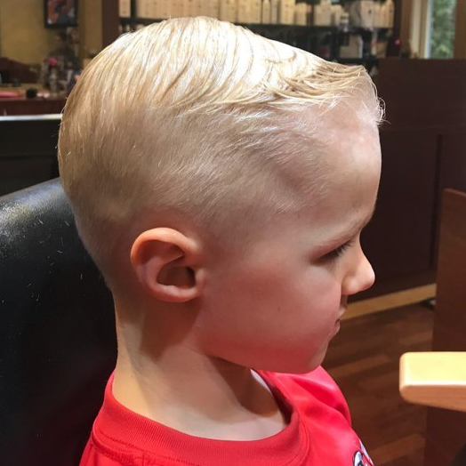 A young boy with blonde hair is wearing a red shirt