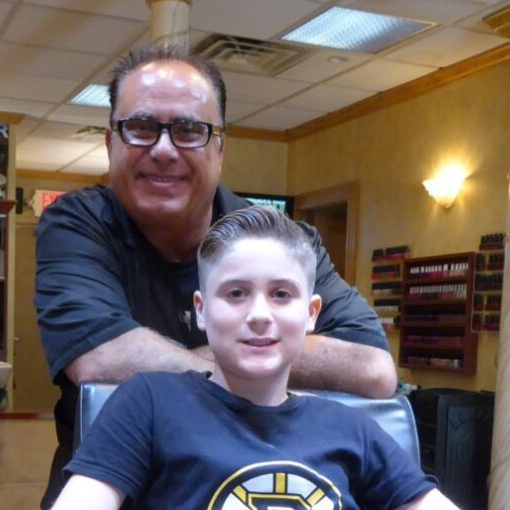 A man and a boy are posing for a picture in a barber shop