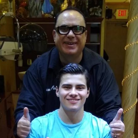 A man and a boy are giving a thumbs up in front of an exit sign