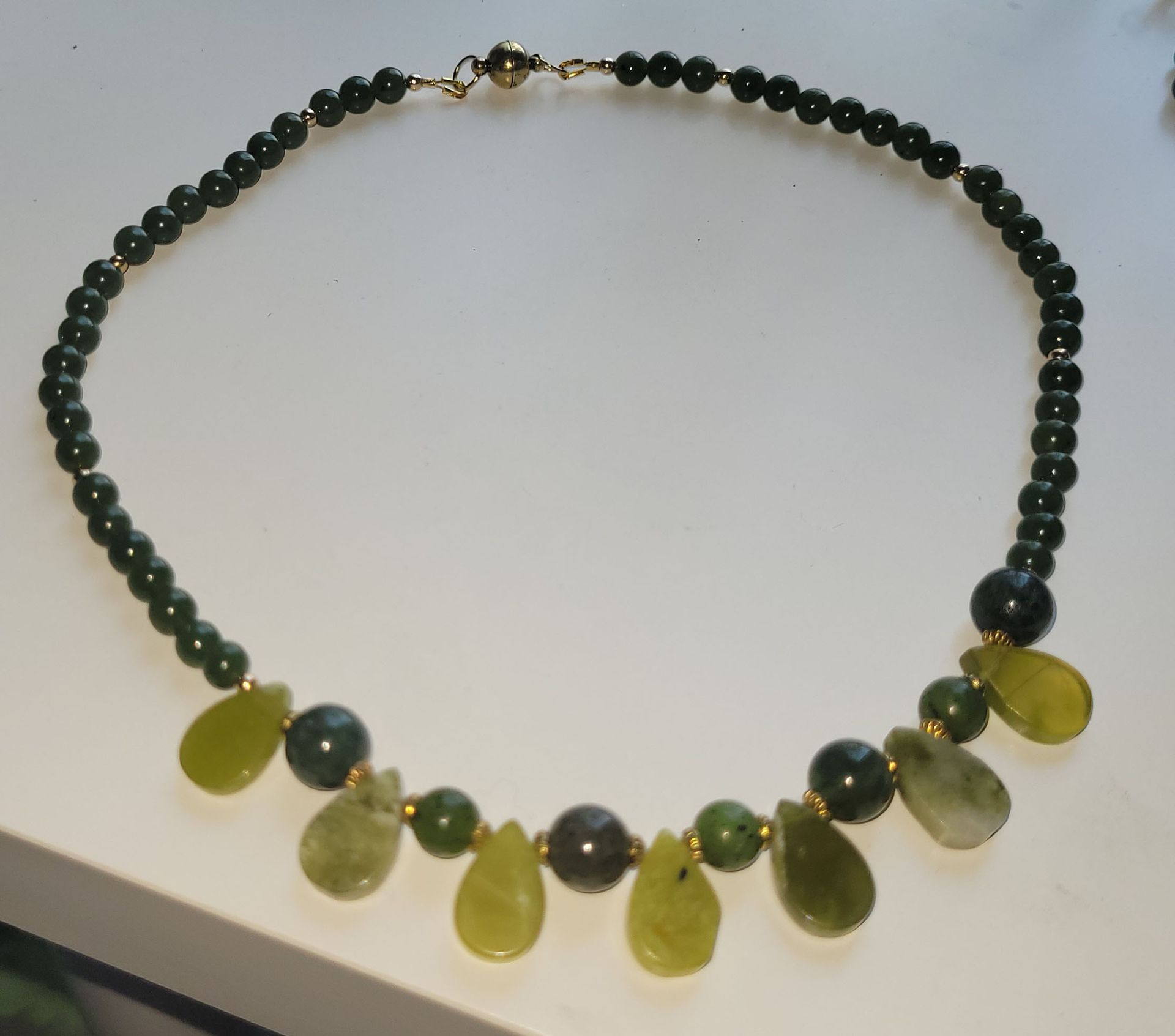 A necklace with green and yellow beads on a white surface
