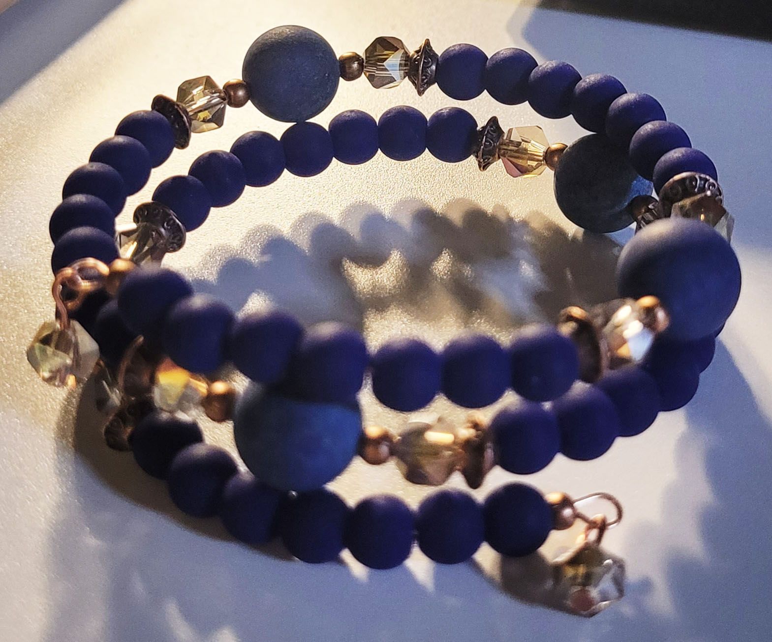 A bracelet with purple beads and gold beads on a white surface