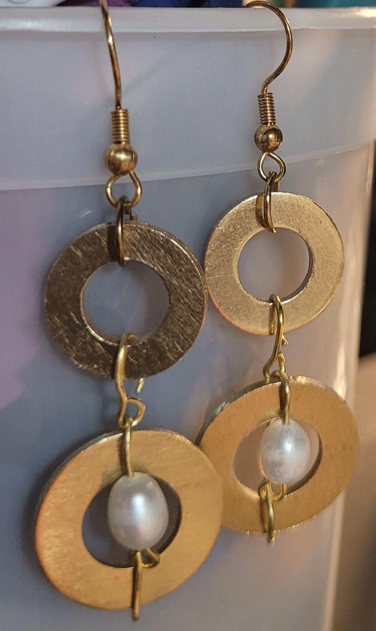 A pair of gold earrings with a pearl in the middle