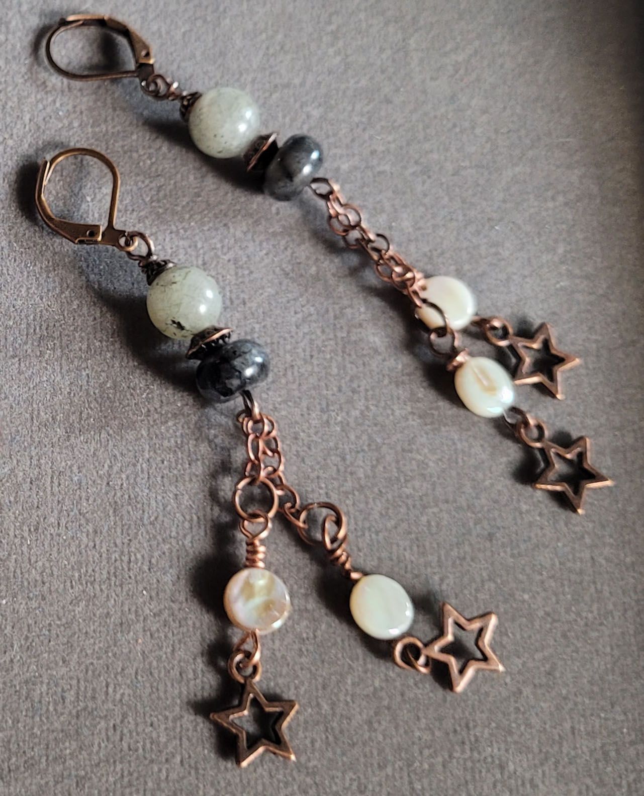 A pair of earrings with beads and stars on them