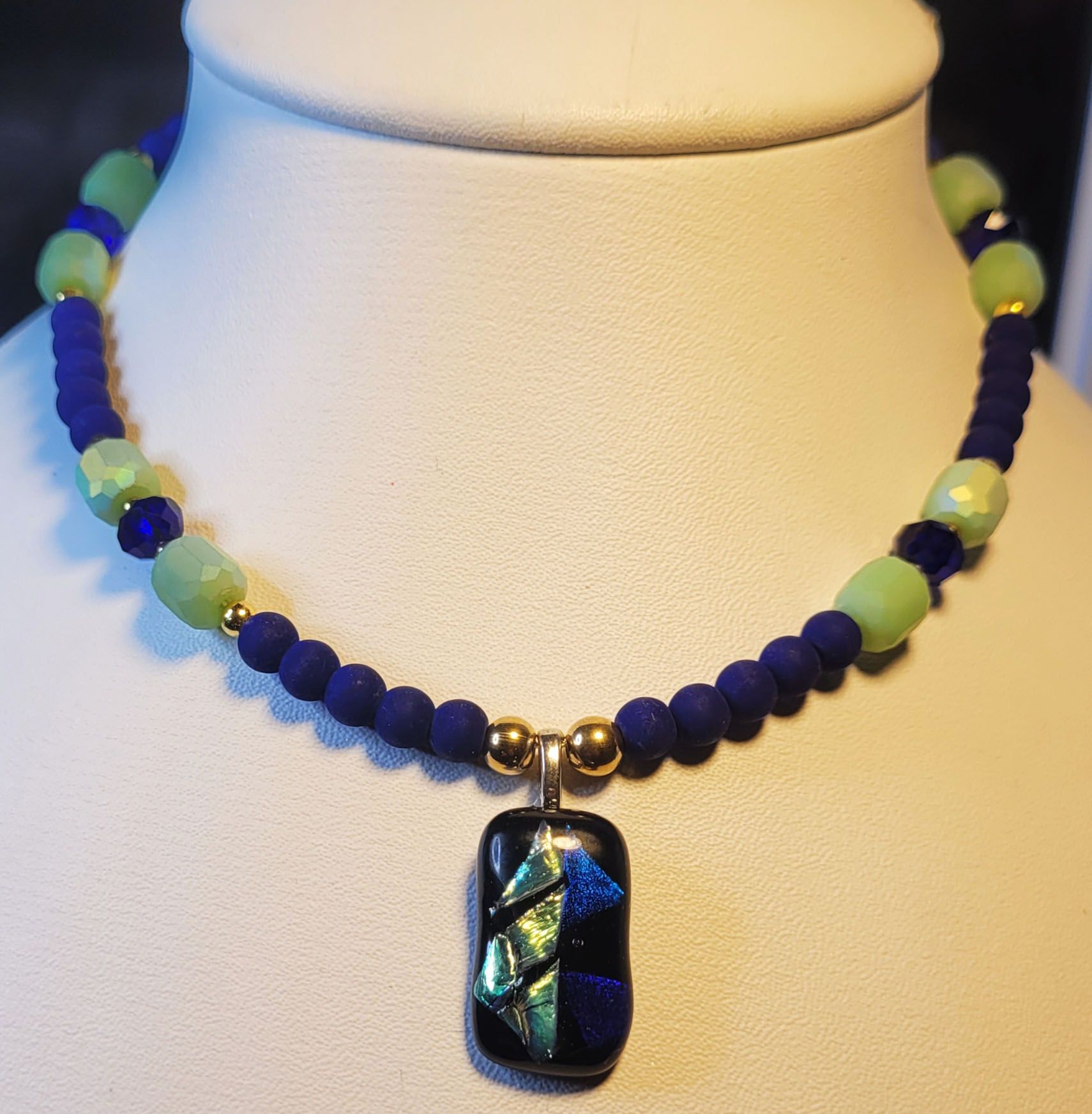 A necklace with blue and green beads and a black pendant
