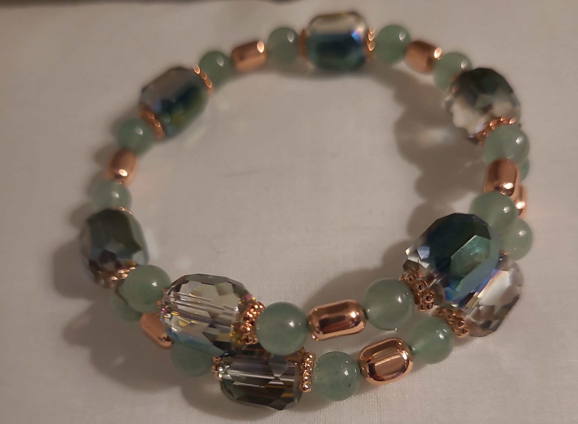 A bracelet with green and clear beads on a white surface