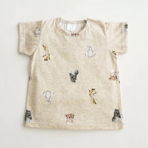 Camiseta beige con pequeños estampados de animales y mangas cortas, extendida sobre un fondo blanco.