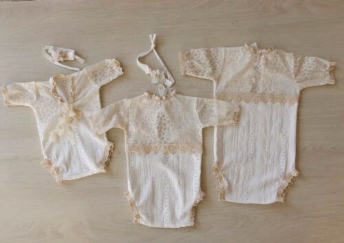 Tres mamelucos de bebé de color crema extendidos sobre una superficie de madera.