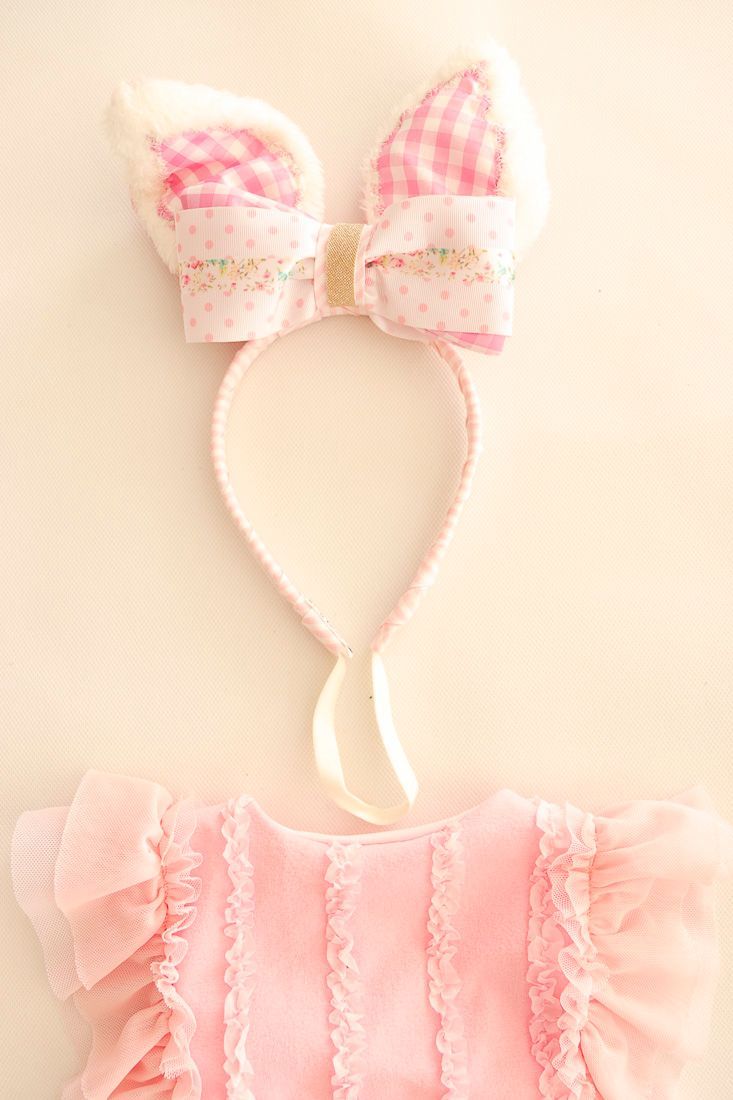 Traje de baño rosa para bebé con gorro a juego, extendido sobre un fondo beige.