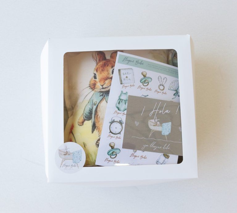 Caja de regalo blanca con una tarjeta ilustrada con un conejo y artículos de papelería en su interior.