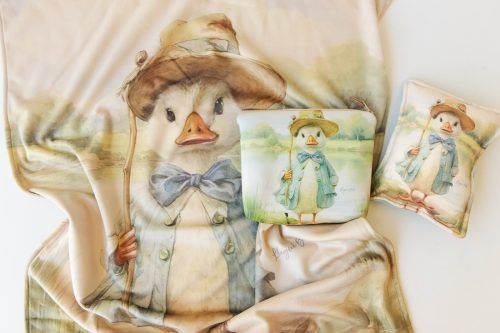 Bonita ilustración de un pato en una camiseta color crema, con estampados de patos a juego en tarjetas cercanas.