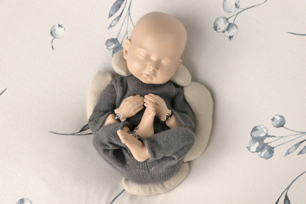 Tela beige doblada, dispuesta en capas con formas circulares y de media luna sobre una superficie de madera clara.