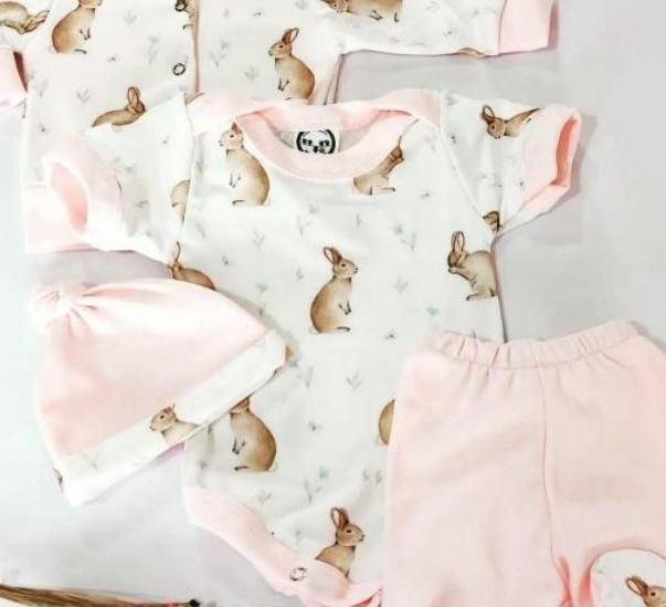 Ropa de bebé en tonos pastel con estampado de conejitos, que incluye un body, pantalones y gorro.