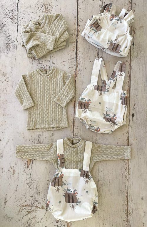 Conjunto de punto infantil a juego en color crema con estampado floral, extendido sobre un suelo de madera.