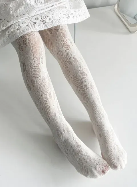 Piernas y pies cubiertos de encaje blanco descansando sobre una cama.