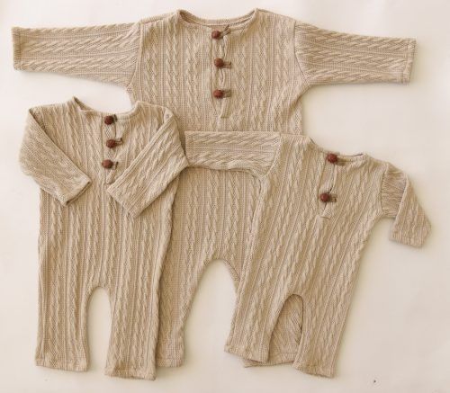 Tres conjuntos de bebé de punto color beige con botones, dispuestos sobre un fondo blanco.