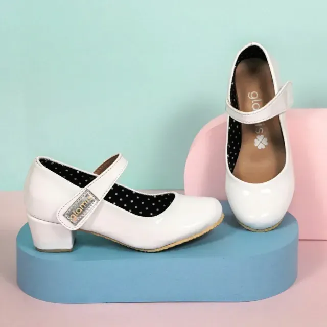 Zapatos blancos estilo Mary Jane con plantillas de lunares negros exhibidos sobre bloques de colores pastel