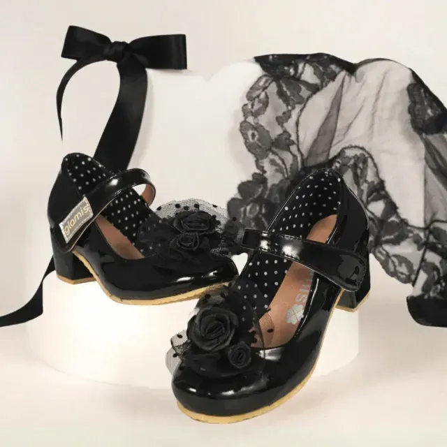 Zapatos de tacón alto de encaje negro con lazos, presentados sobre una tela de encaje negro transparente.