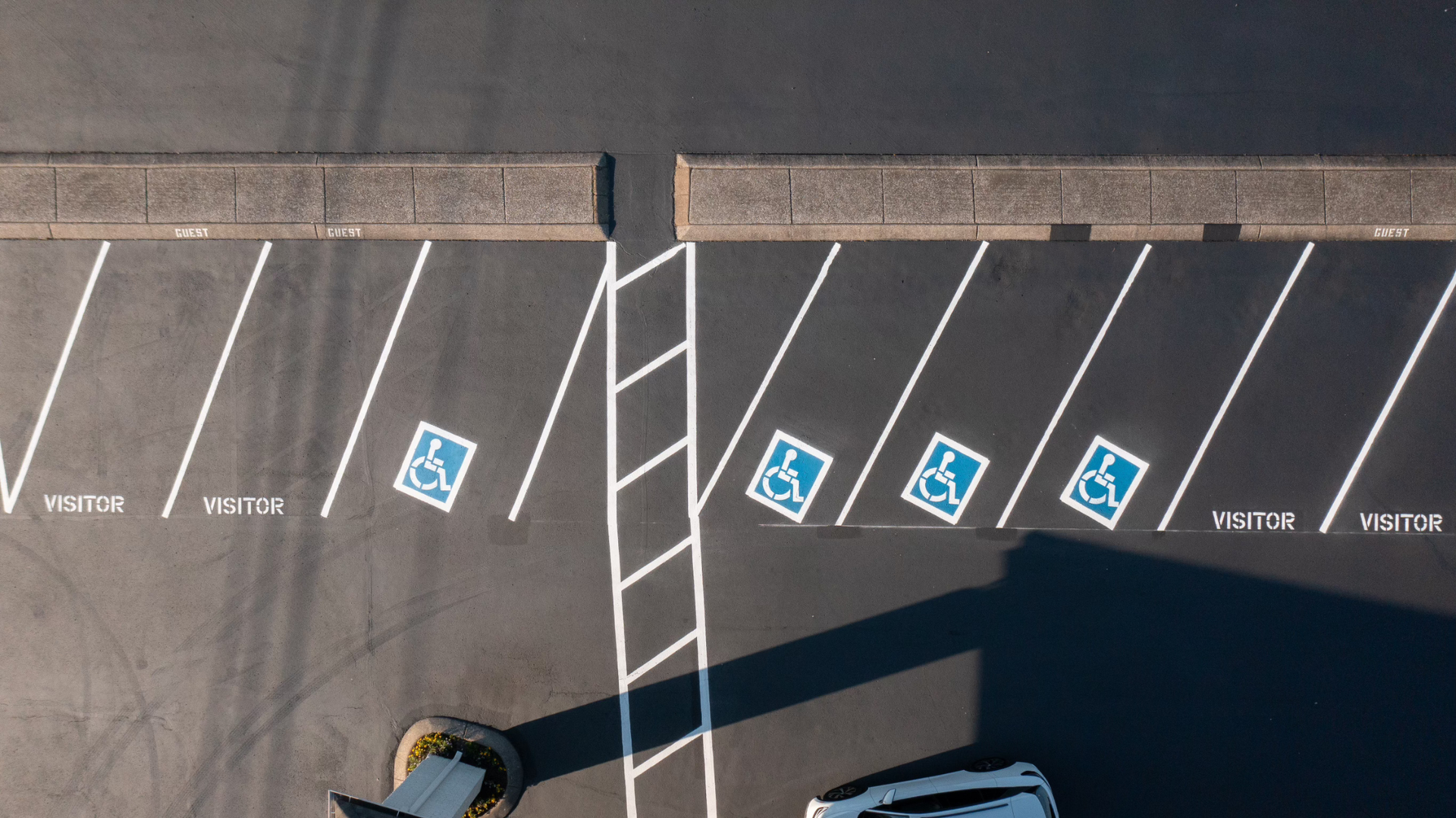 Overhead view of parking lot with disabled parking spaces marked with blue wheelchair symbol.