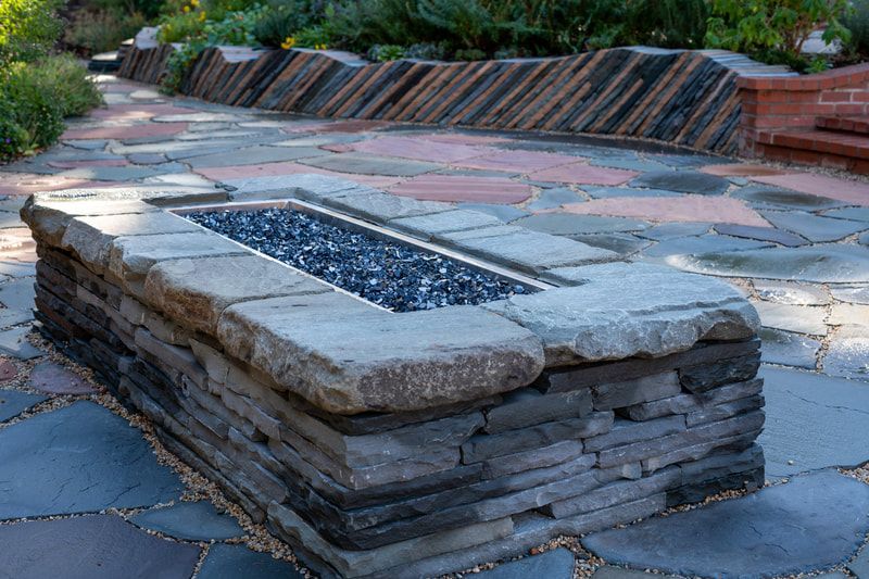 A stone fire pit is sitting on top of a stone patio.