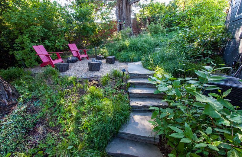 There are stairs leading up to a patio with red chairs.