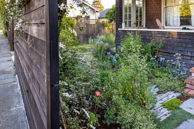 A wooden fence surrounds a garden in front of a house.