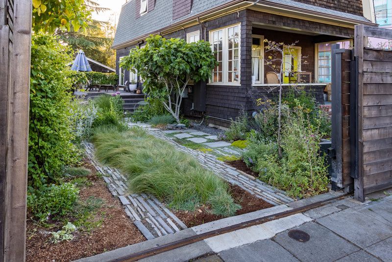 A black house with a lush green garden in front of it.