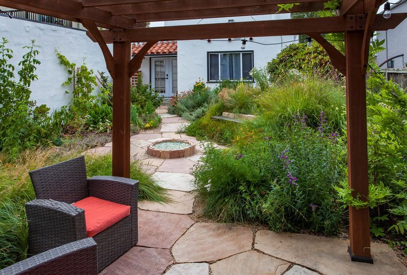 There is a chair under a pergola in the backyard.