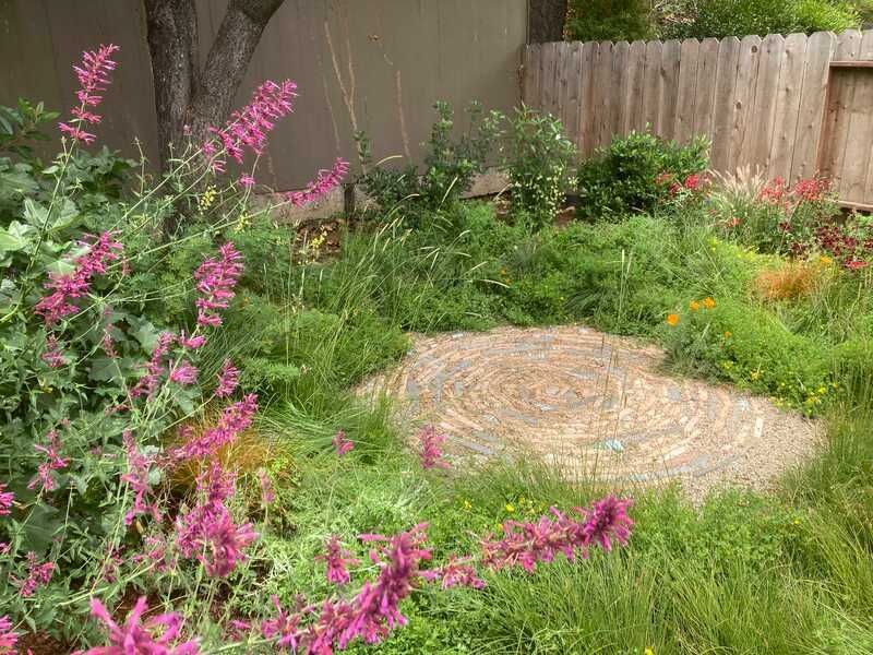 A garden with purple flowers and a stone circle in the middle of it.