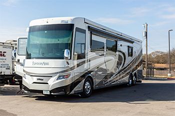 Large white and silver recreational vehicle parked outside.
