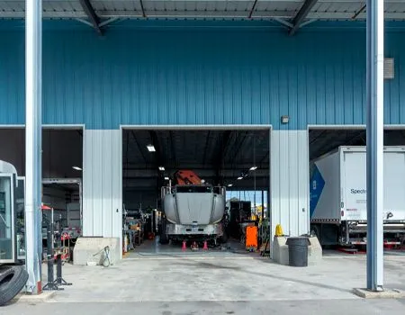 Truck and workers inside a blue industrial garage bay