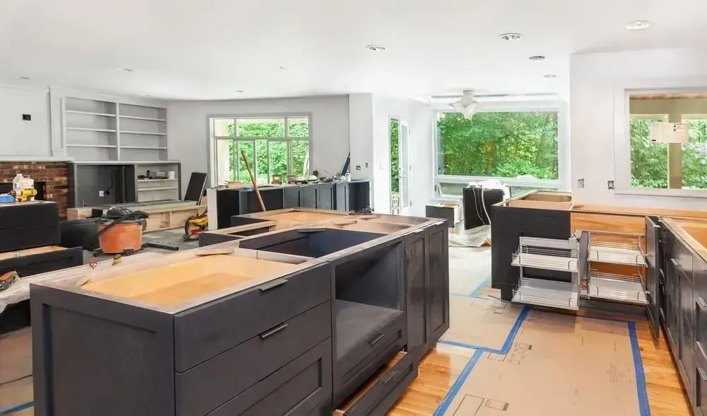 Renovation in progress in a bright kitchen with cabinets, countertops, and cardboard floor protection