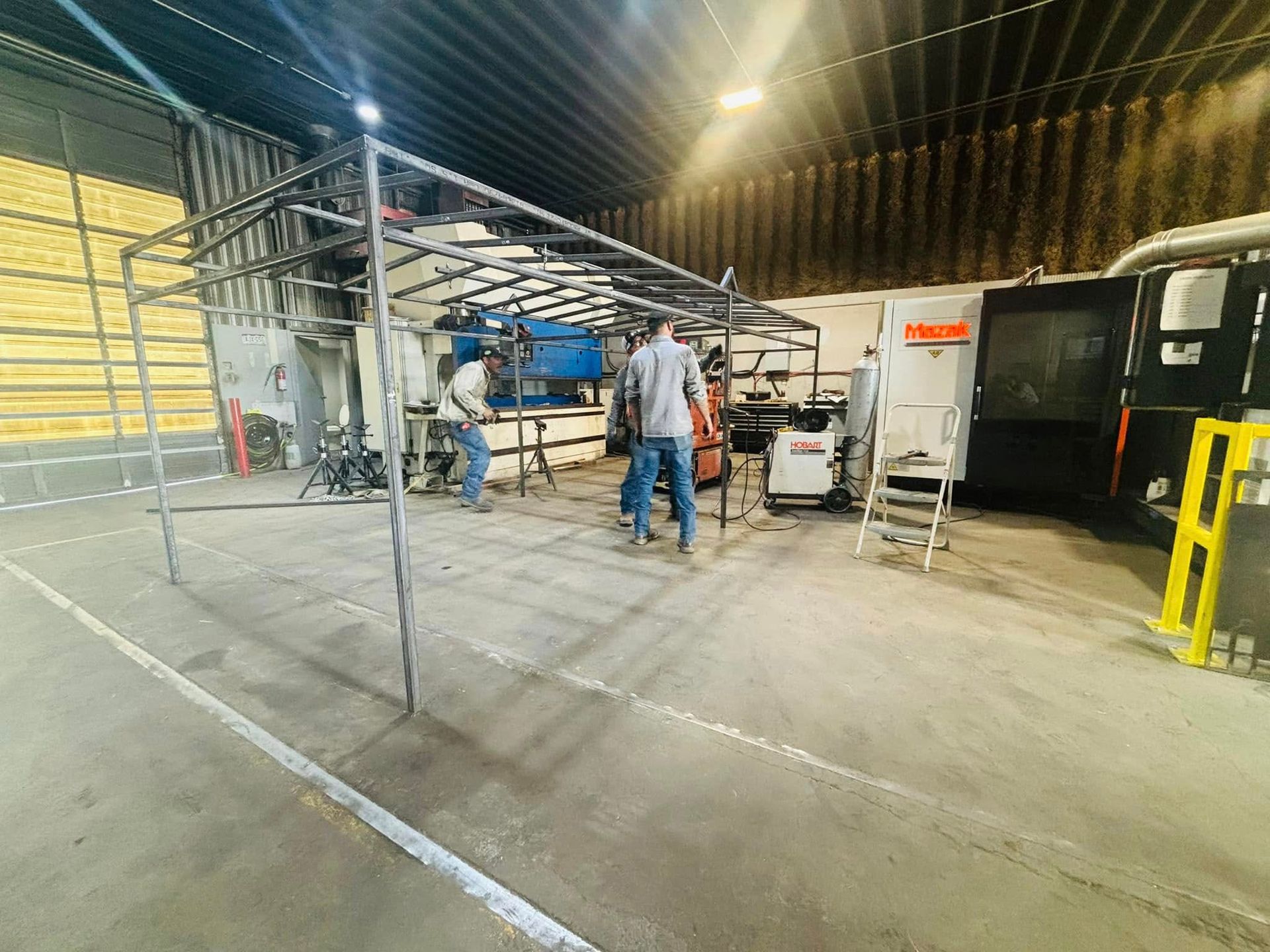 A group of people are working on a metal structure in a factory.
