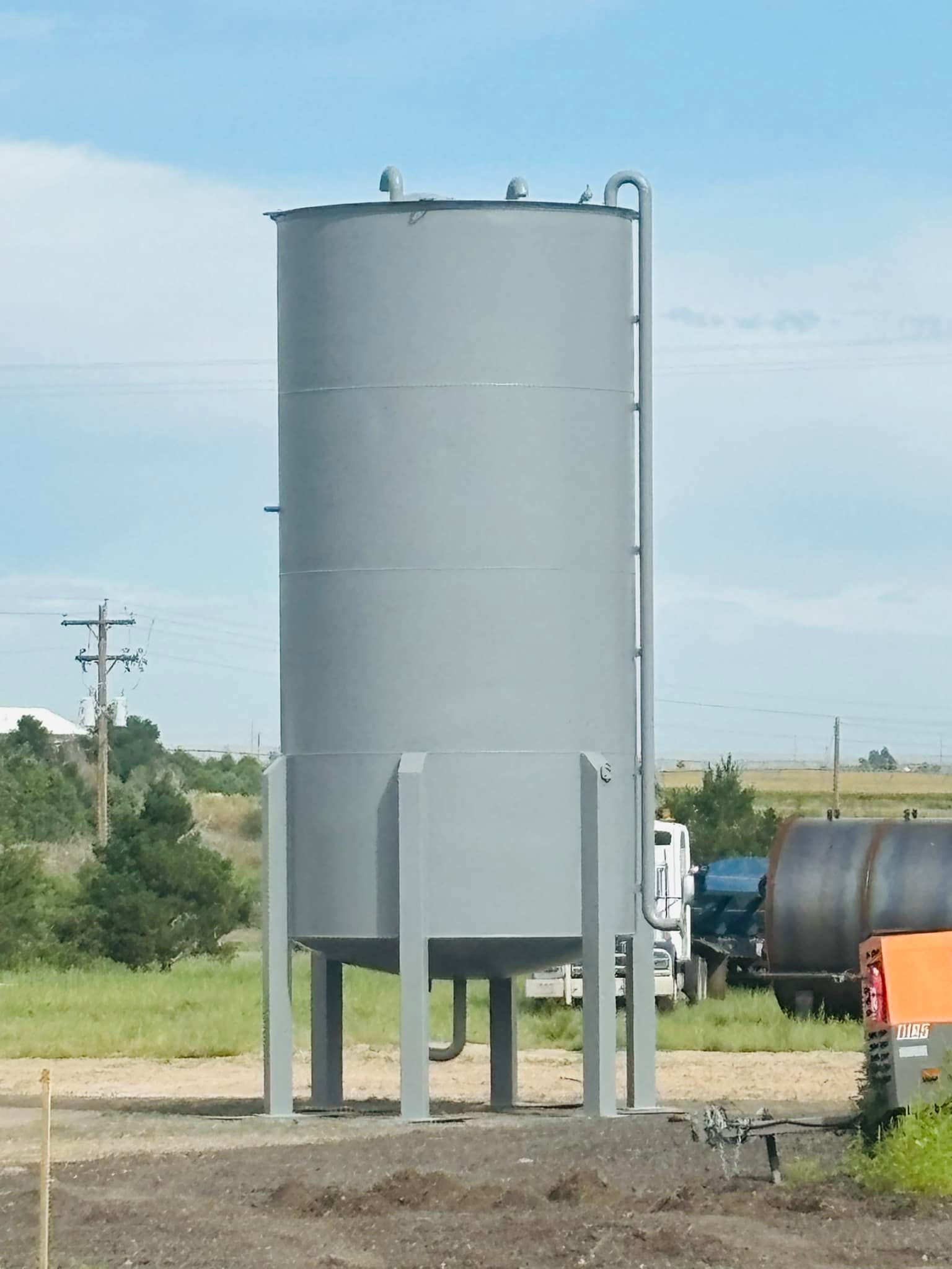 A large gray tank sits in the middle of a field