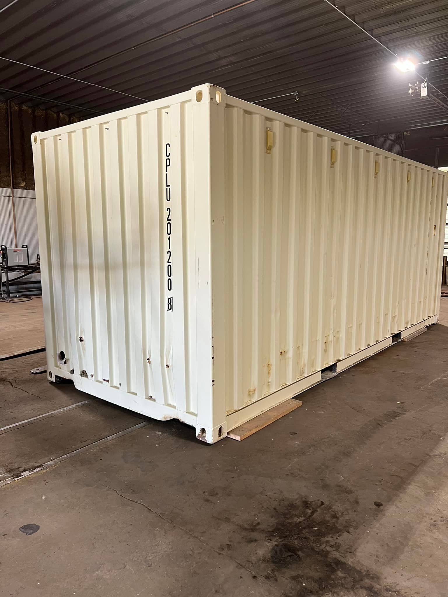 A large white shipping container is sitting in a warehouse.