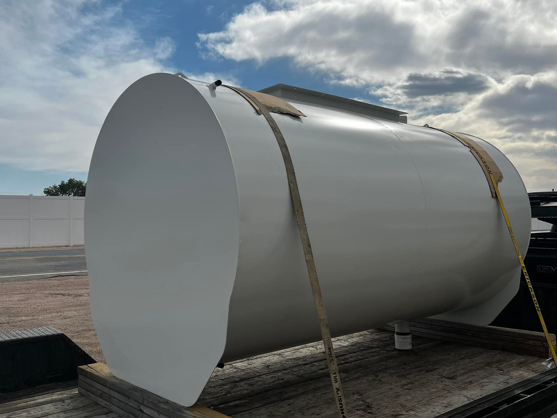 A large white cylinder is tied to a truck with a rope.