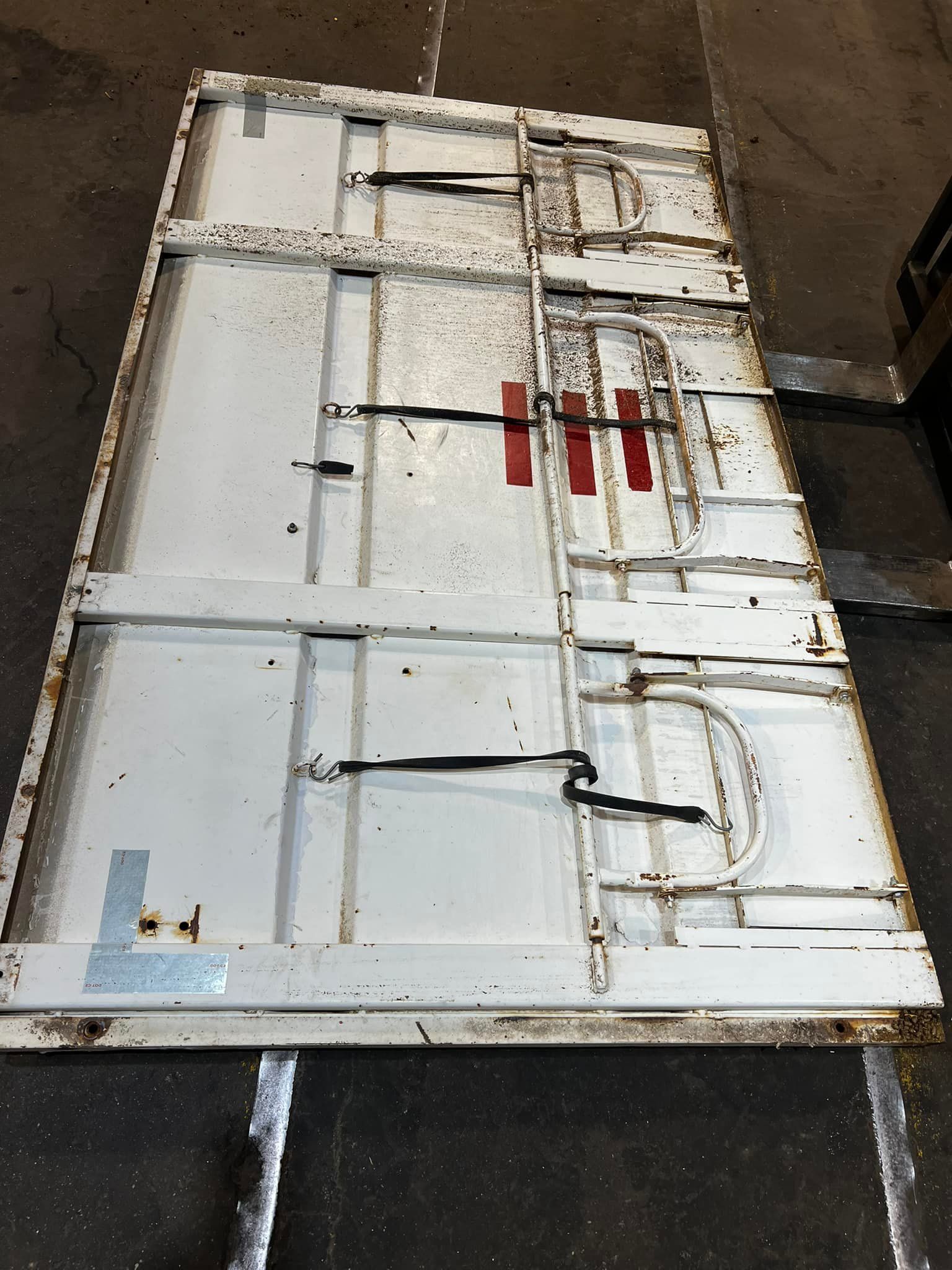 A large piece of metal is sitting on the ground next to a forklift.
