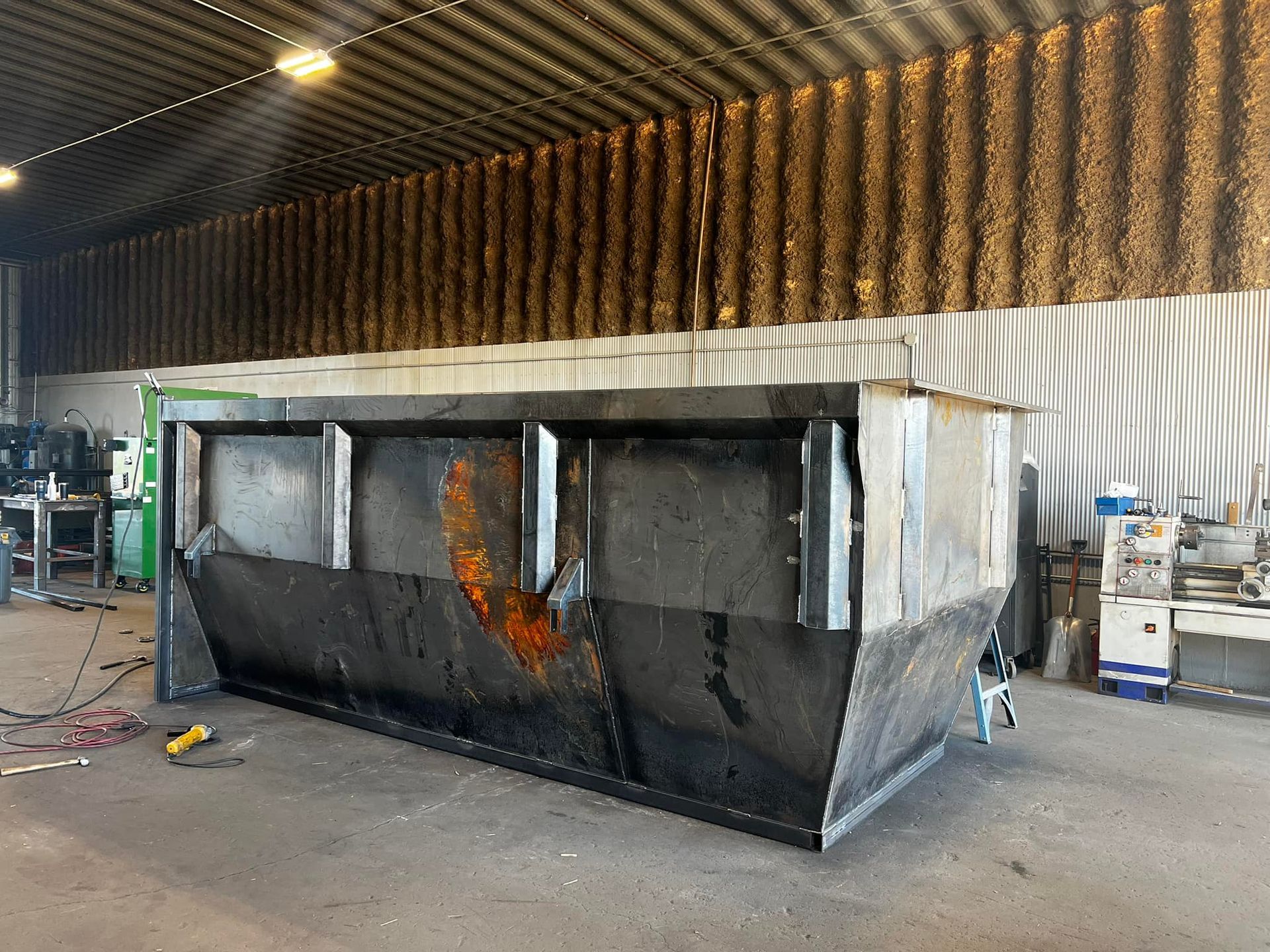 A large metal dumpster is sitting in a warehouse.