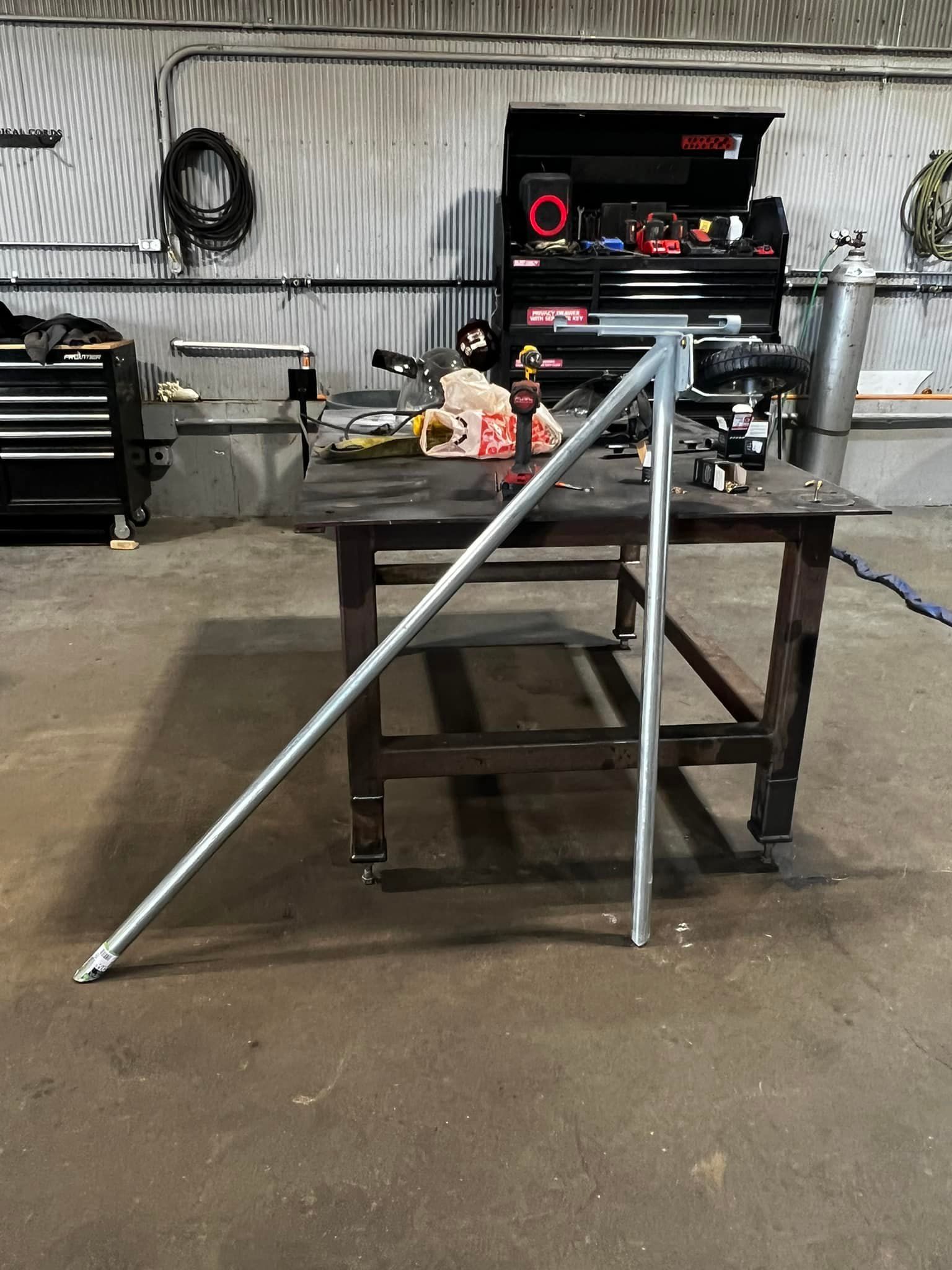 A metal pole is sitting on top of a wooden table in a workshop.