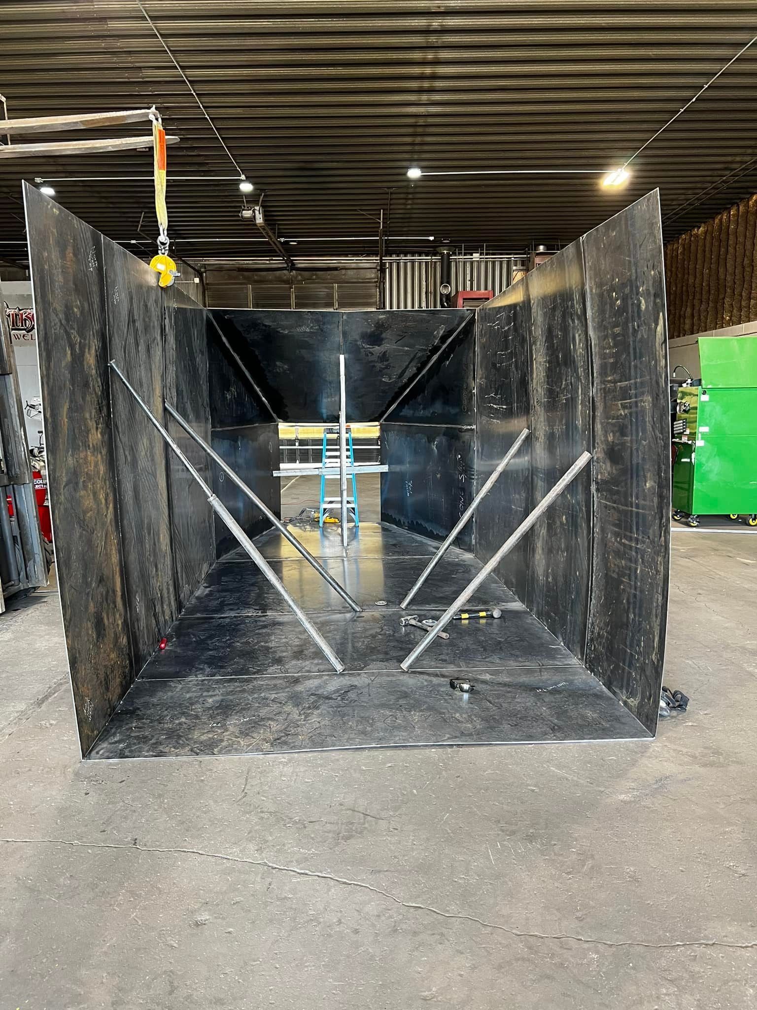 A large metal box is sitting on the ground in a warehouse.