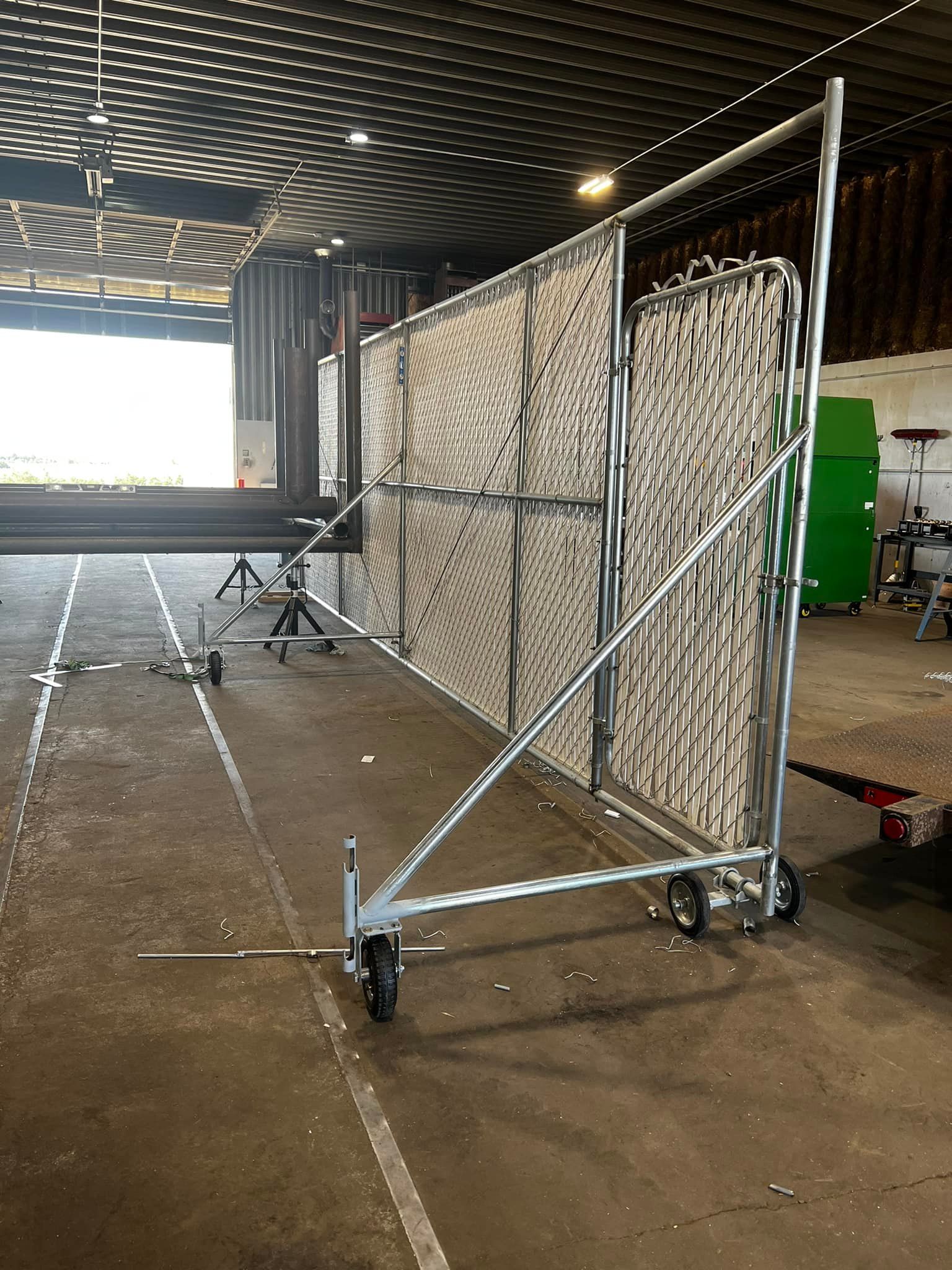 A metal fence with wheels is sitting in a warehouse.
