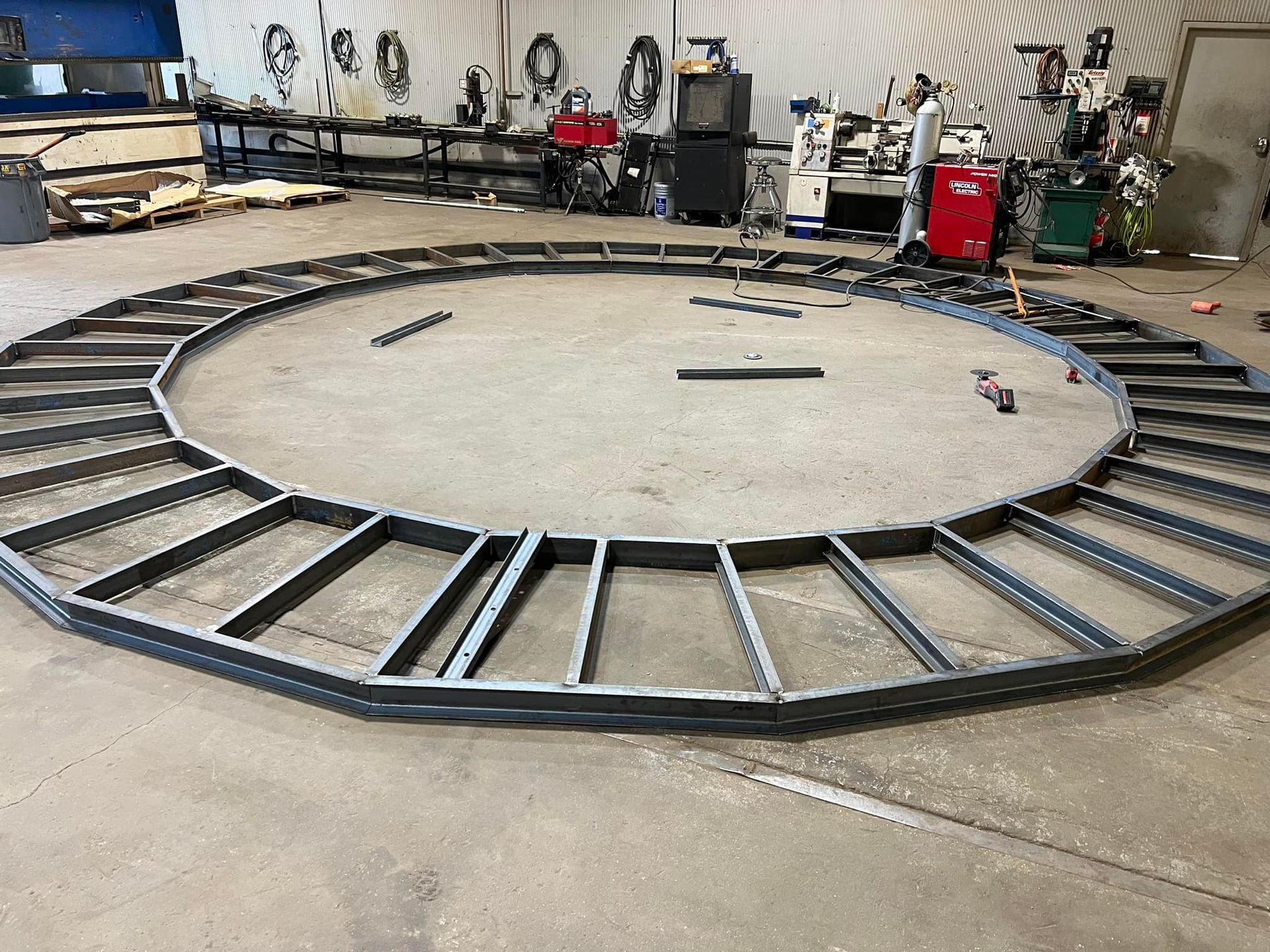 A large metal clock is being built in a factory.