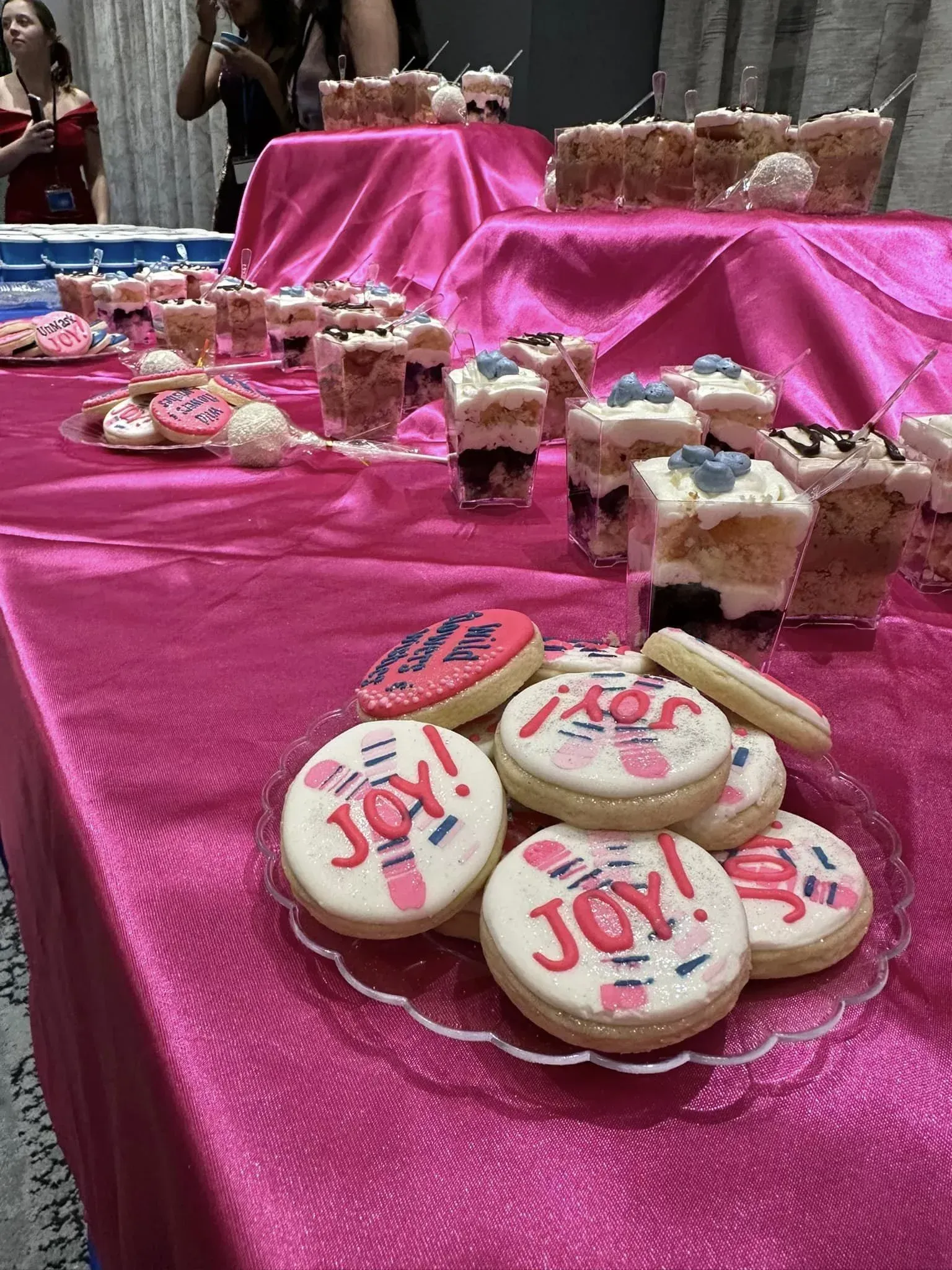Pink dessert table with cookies, parfaits, and other sweets.
