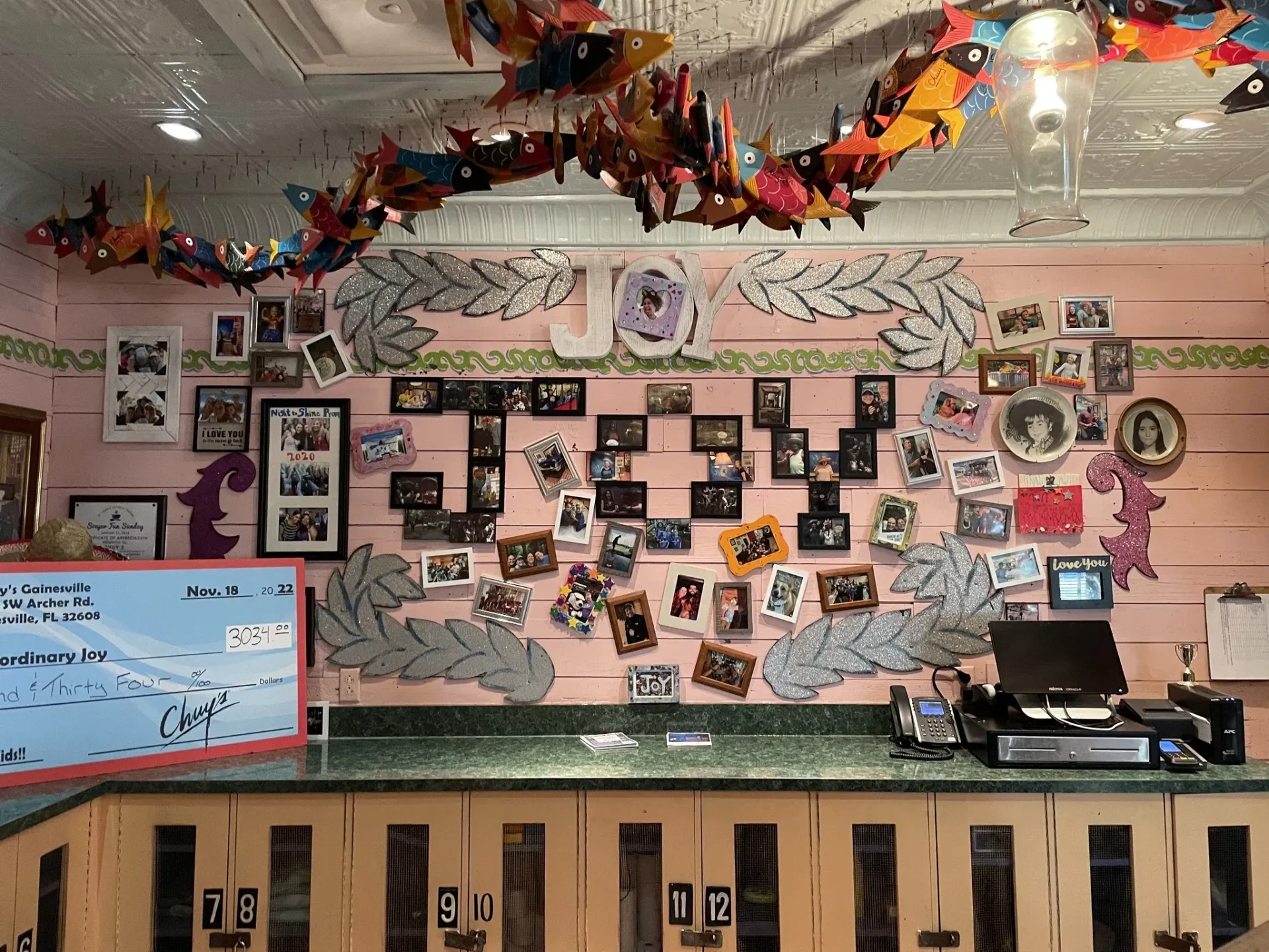 Counter with framed photos, decorations and model airplanes on a pink wall.