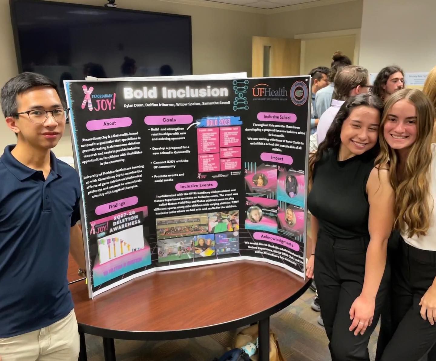 Three people stand with a poster titled