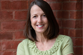 Smiling woman in a light green top against a red brick wall