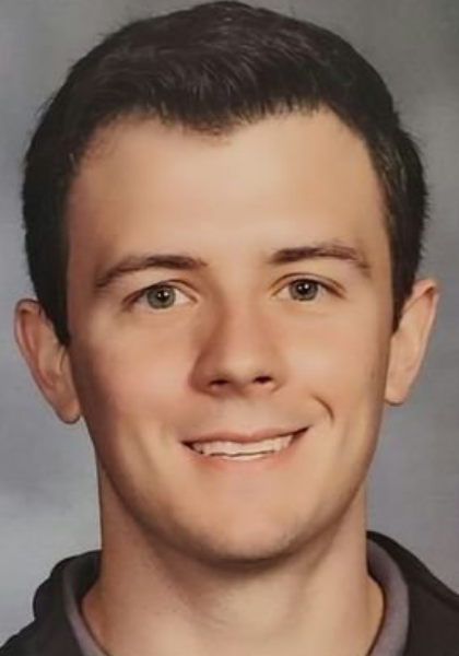 Studio headshot of a smiling person in a dark shirt against a gray background