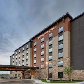 Exterior of a modern hotel building with brown and gray facade and covered entrance