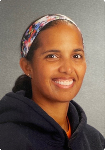 Smiling person in a navy hoodie and floral headband against a gray background
